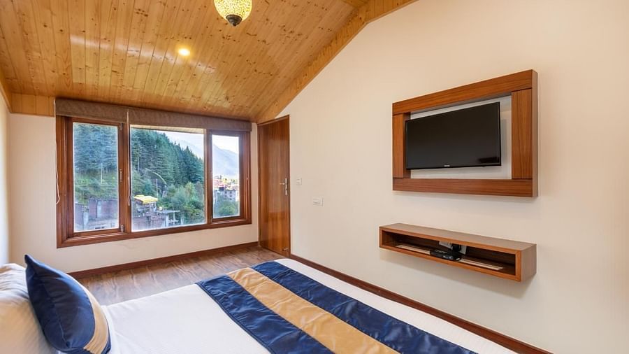 Image of a bedroom with a king size bed, a flat-screen TV mounted on the wall, and large windows  | DLS Serenity Resort and Spa